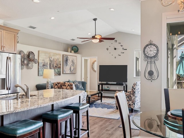 kitchen with light brown cabinets, lofted ceiling, sink, light hardwood / wood-style flooring, and stainless steel fridge