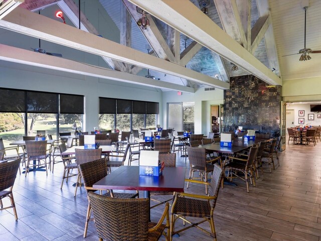 dining space featuring beamed ceiling, hardwood / wood-style flooring, high vaulted ceiling, and ceiling fan