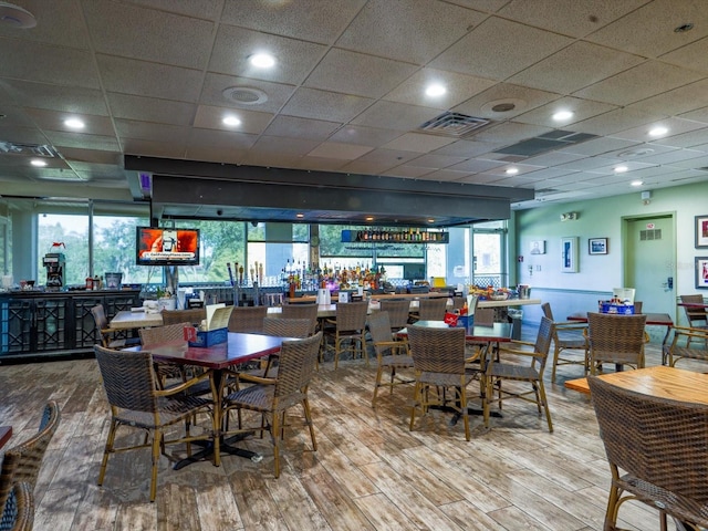 dining space featuring a paneled ceiling, hardwood / wood-style floors, and a healthy amount of sunlight