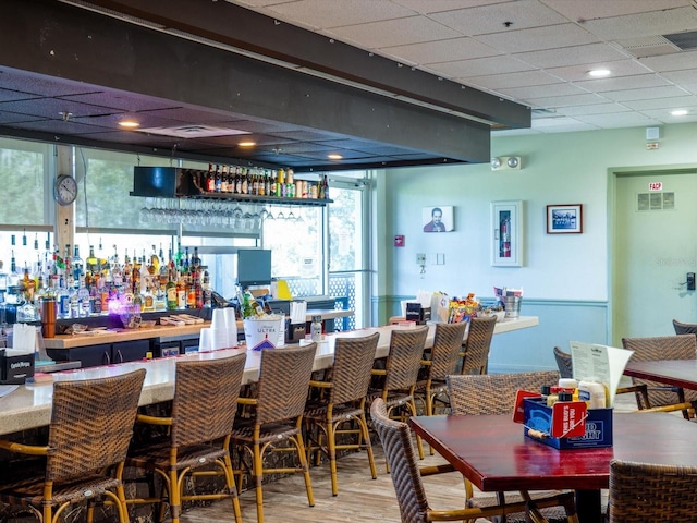 bar with a paneled ceiling, a wealth of natural light, and hardwood / wood-style floors