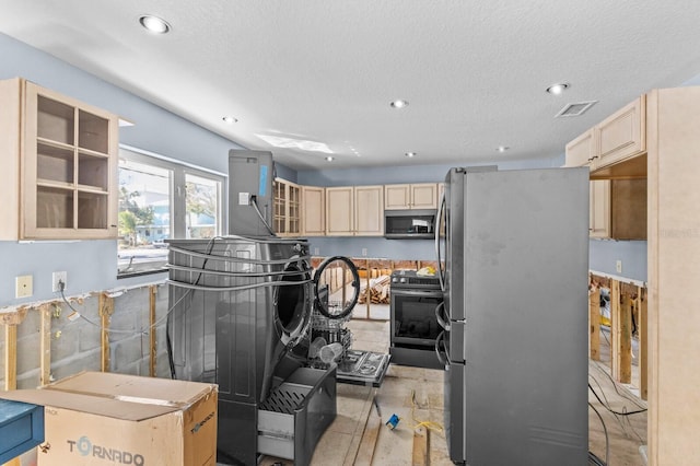 kitchen featuring a textured ceiling, stainless steel appliances, and light brown cabinetry