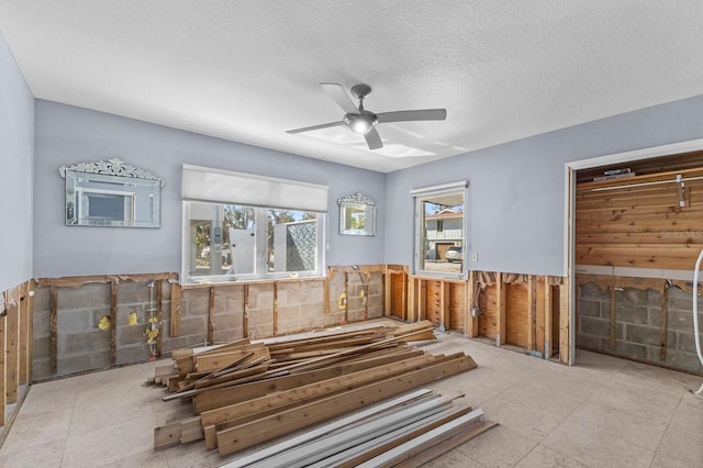 miscellaneous room featuring a textured ceiling, ceiling fan, and tile walls