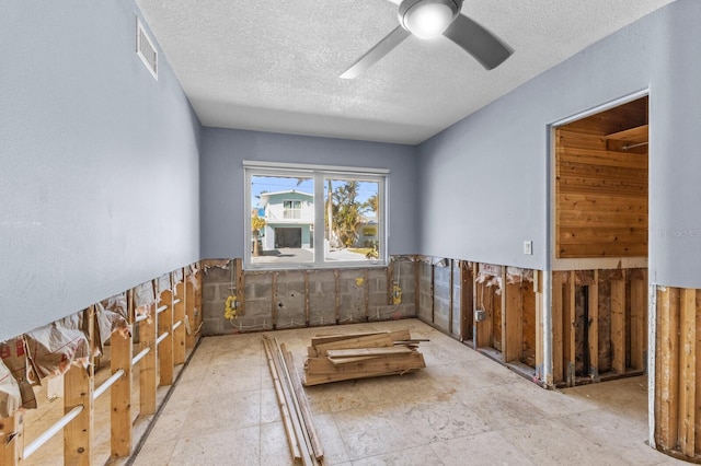 unfurnished room with tile walls, ceiling fan, and a textured ceiling