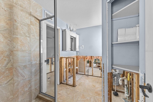 bathroom with a textured ceiling and a shower with door