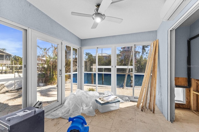 unfurnished sunroom featuring ceiling fan and an AC wall unit