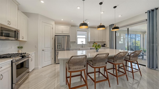 kitchen with white cabinetry, backsplash, pendant lighting, a kitchen island, and appliances with stainless steel finishes