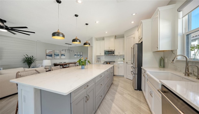 kitchen featuring appliances with stainless steel finishes, white cabinetry, a large island, and sink