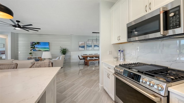 kitchen featuring decorative backsplash, white cabinets, stainless steel appliances, and light stone counters