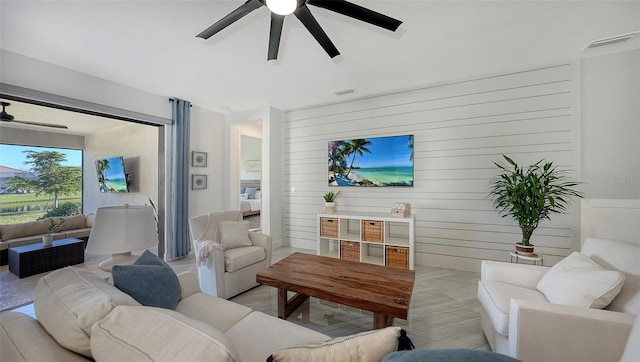 living room with ceiling fan and wood walls