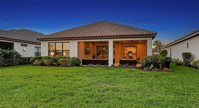 back of property with a yard and ceiling fan