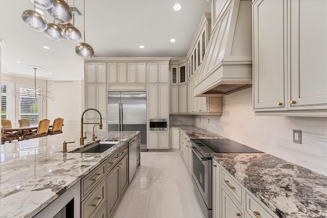 kitchen featuring sink, hanging light fixtures, custom range hood, stainless steel appliances, and cream cabinetry