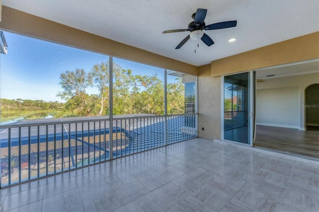 unfurnished sunroom with ceiling fan