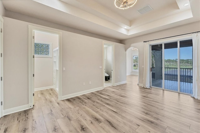 unfurnished room featuring light wood-type flooring and a tray ceiling