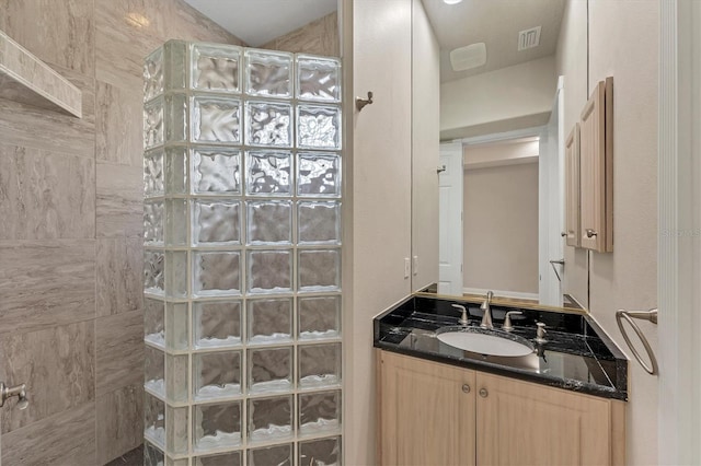 bathroom with a tile shower and vanity