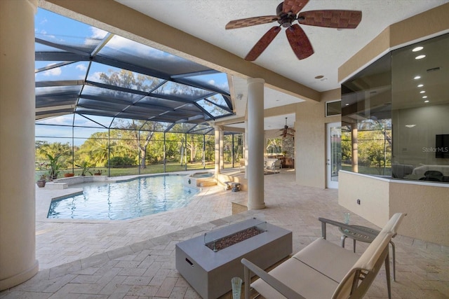 view of swimming pool featuring glass enclosure, a patio area, ceiling fan, and a fire pit