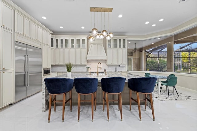 kitchen featuring built in refrigerator, a spacious island, glass insert cabinets, and backsplash