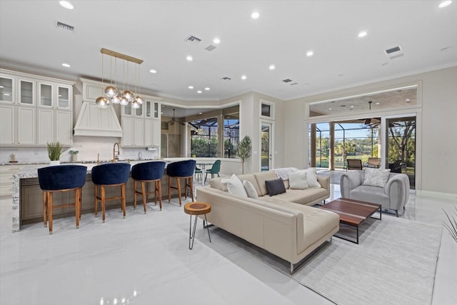 living area with recessed lighting, marble finish floor, visible vents, and crown molding