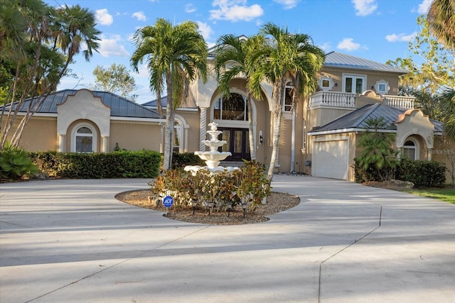 mediterranean / spanish-style home with driveway, french doors, a balcony, and stucco siding