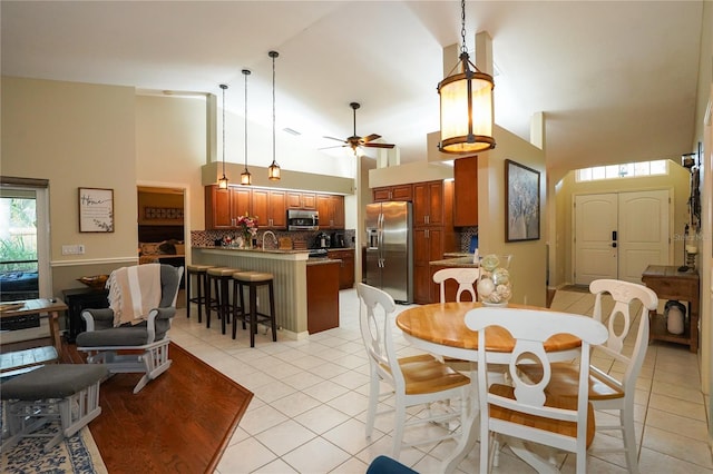 dining area with light tile patterned floors, high vaulted ceiling, and ceiling fan