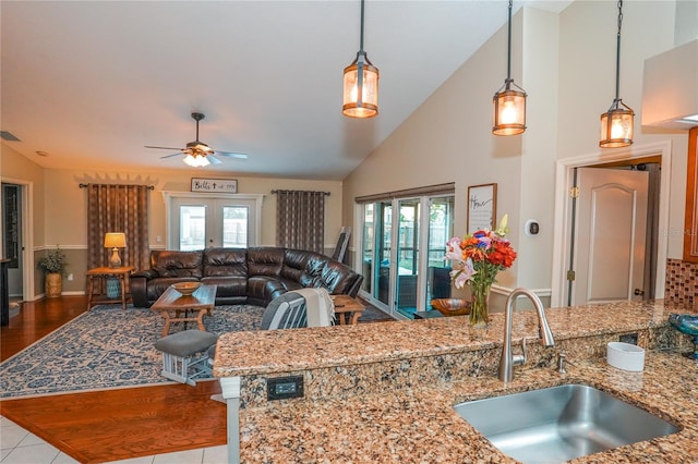 kitchen featuring light stone countertops, sink, pendant lighting, and french doors