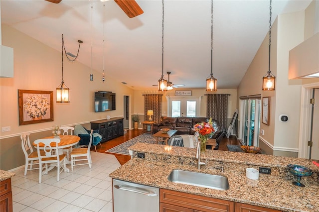 kitchen with light stone counters, stainless steel dishwasher, sink, hanging light fixtures, and light tile patterned flooring