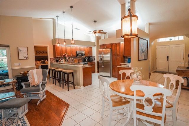 tiled dining area with ceiling fan, sink, and high vaulted ceiling