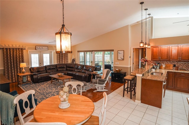 tiled living room with french doors, ceiling fan with notable chandelier, a wealth of natural light, and sink