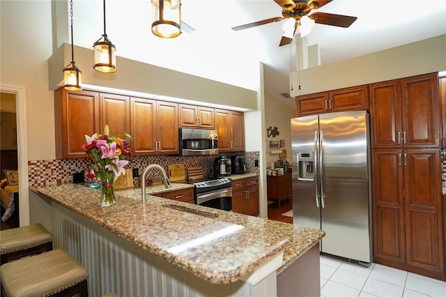 kitchen with kitchen peninsula, light stone counters, a breakfast bar, and appliances with stainless steel finishes