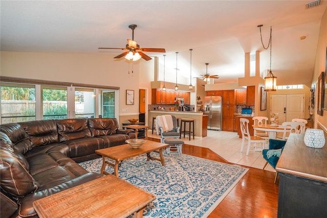 living room featuring light wood-type flooring, high vaulted ceiling, and ceiling fan