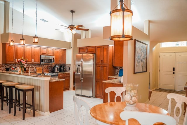 kitchen with kitchen peninsula, decorative backsplash, a breakfast bar, and stainless steel appliances