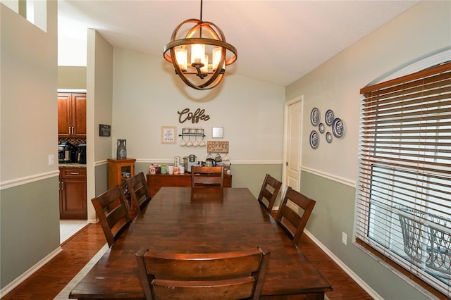 dining space with a chandelier, dark hardwood / wood-style flooring, and vaulted ceiling