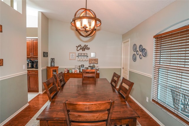 dining space featuring hardwood / wood-style floors, lofted ceiling, and a notable chandelier