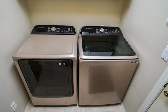 clothes washing area featuring light tile patterned floors and washer and dryer