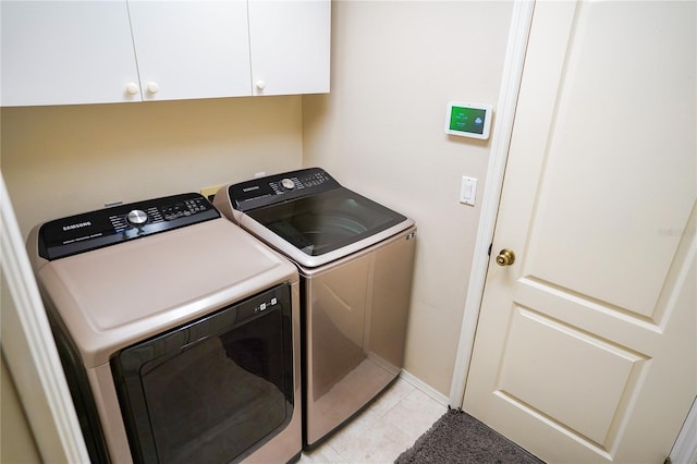 laundry room with washer and clothes dryer, light tile patterned flooring, and cabinets