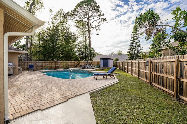 view of pool with a patio, pool water feature, a yard, a shed, and a grill