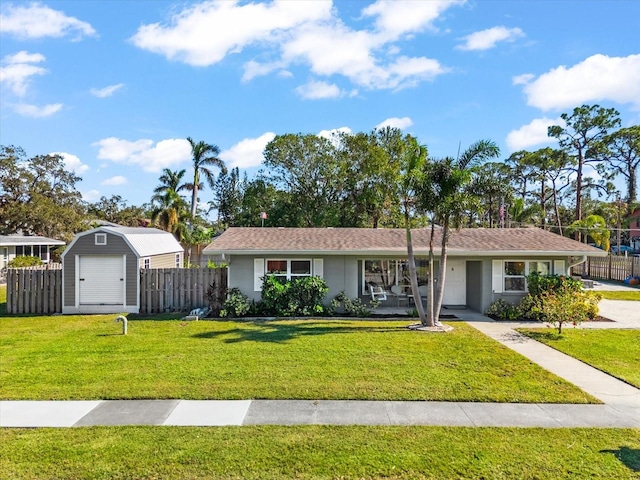 ranch-style house featuring a front lawn and a storage unit