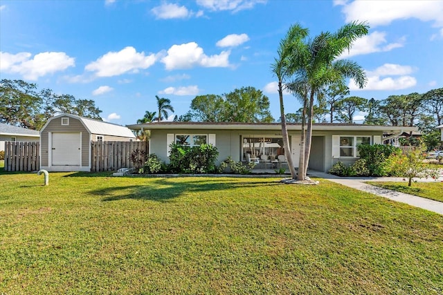 ranch-style home featuring a front yard and a storage unit