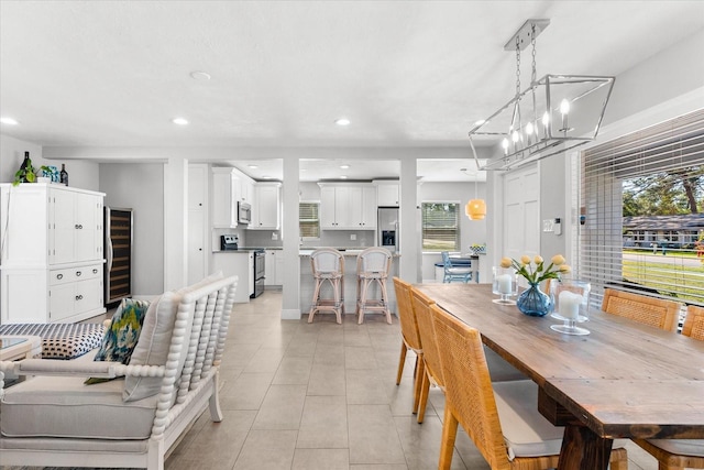 dining area with light tile patterned floors, beverage cooler, and a notable chandelier