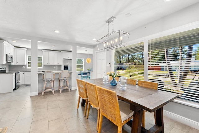 dining room featuring a wealth of natural light, light tile patterned floors, and a chandelier