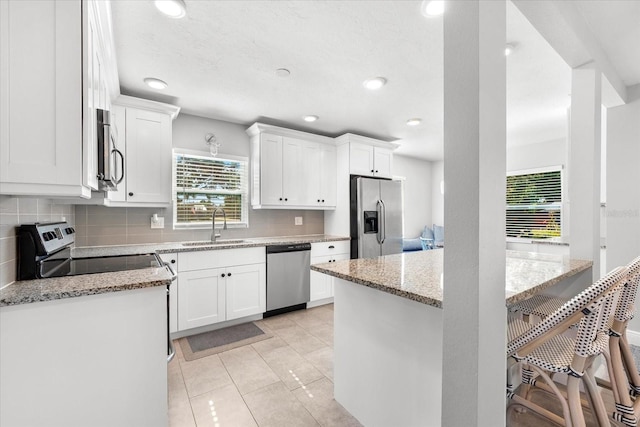 kitchen featuring light stone counters, white cabinetry, sink, and appliances with stainless steel finishes