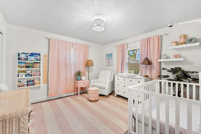 bedroom with a crib and a textured ceiling