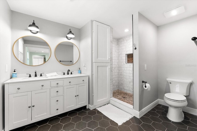 bathroom featuring tile patterned floors, toilet, a tile shower, and vanity