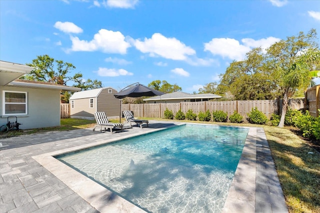 view of swimming pool featuring a patio area and a shed