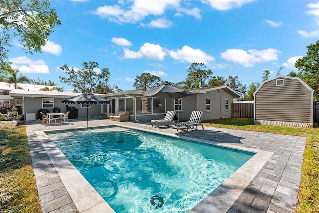 view of pool with a patio area, a sunroom, and a shed