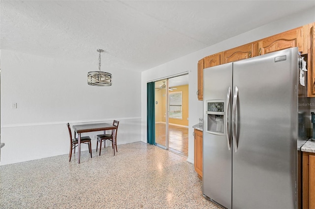 kitchen with stainless steel fridge with ice dispenser, a textured ceiling, decorative light fixtures, and ceiling fan