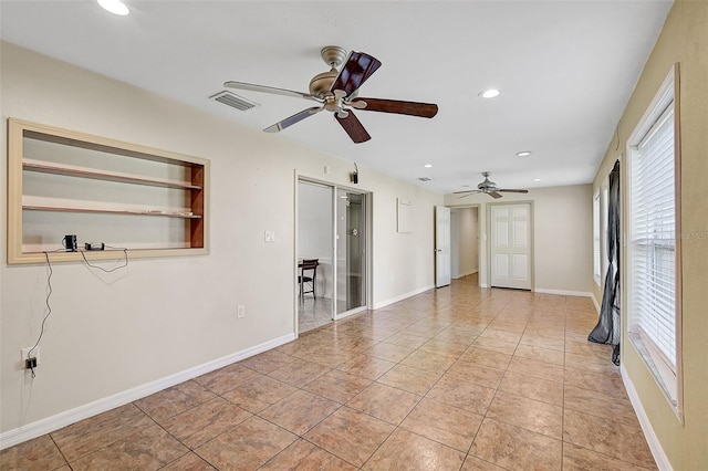 tiled empty room featuring built in shelves and ceiling fan