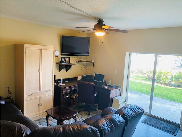 living room featuring ceiling fan and a textured ceiling