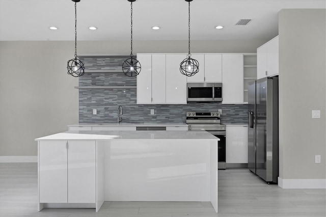 kitchen with pendant lighting, backsplash, sink, appliances with stainless steel finishes, and white cabinetry