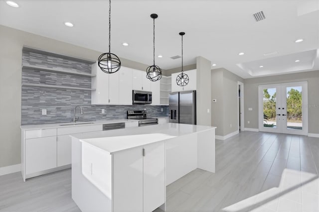 kitchen featuring pendant lighting, a center island, sink, appliances with stainless steel finishes, and white cabinetry