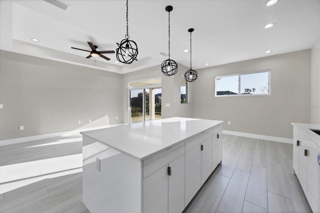 kitchen with white cabinets, a large island, light hardwood / wood-style floors, and decorative light fixtures